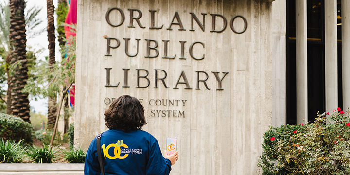 A person in front of the Orlando Public Liibrary