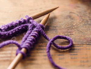 Two knitting needles with purple yarn