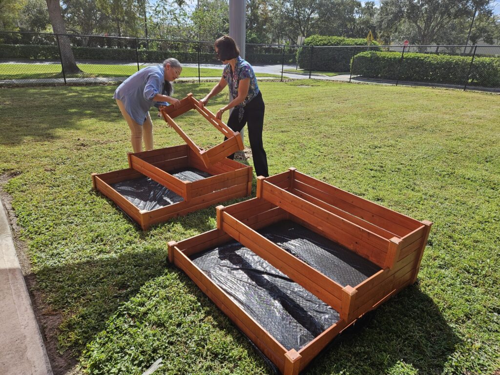 Two staff members assembling a raised garden bed.