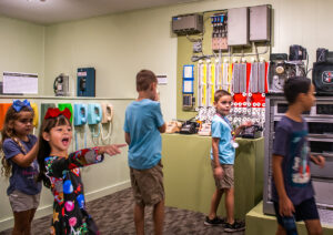 Art & History Center of Maitland's Telephone Museum. Children exploring an exhibit with vintage telephones and telephone equipment.